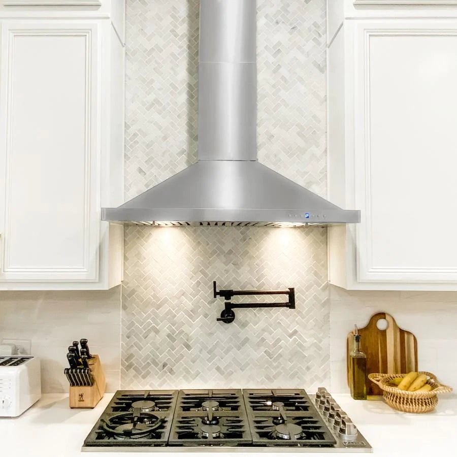 Stainless range hood above a gas cooktop with burner grates and wall backsplash
