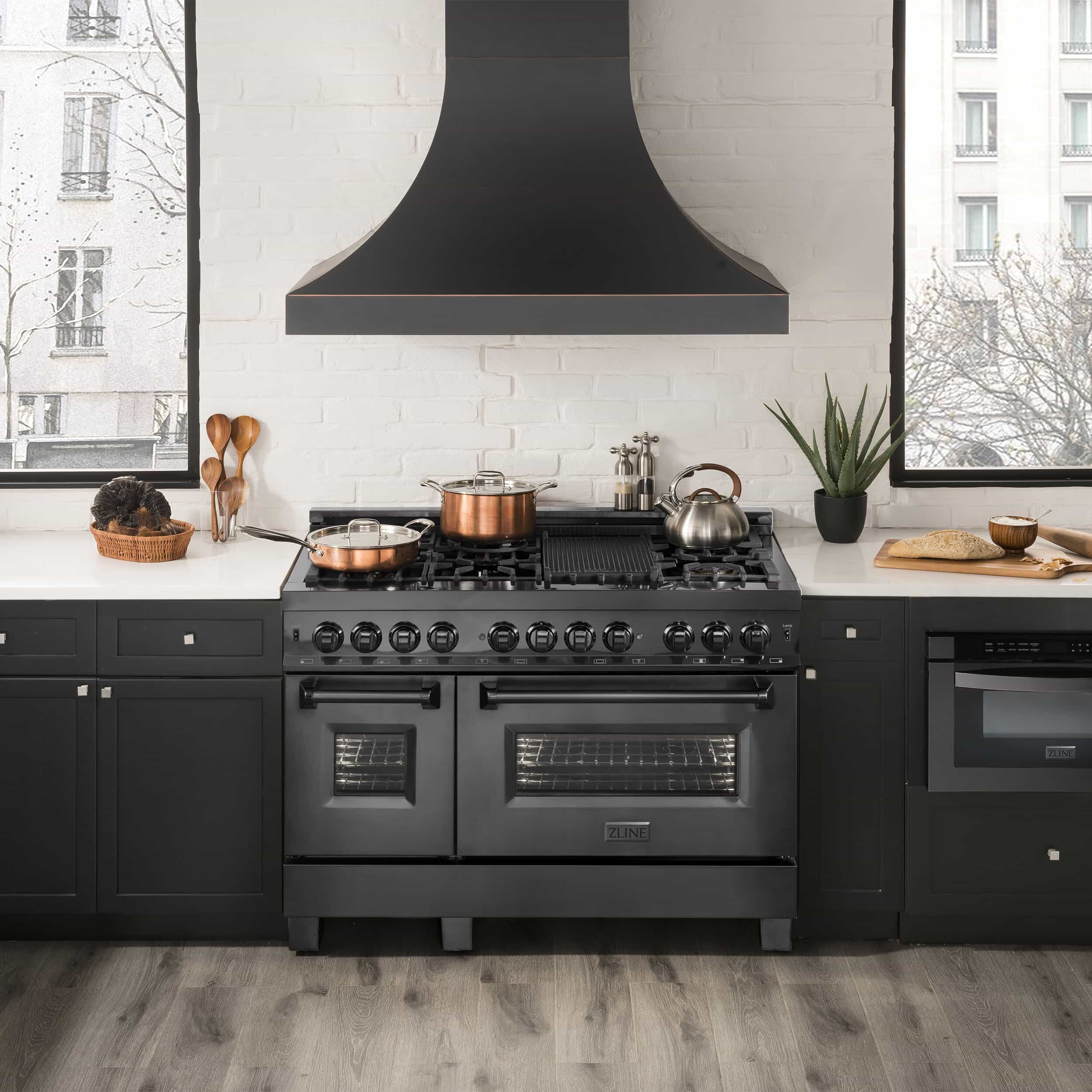 Black dual fuel range with large cooktop, black grates, and two oven doors.