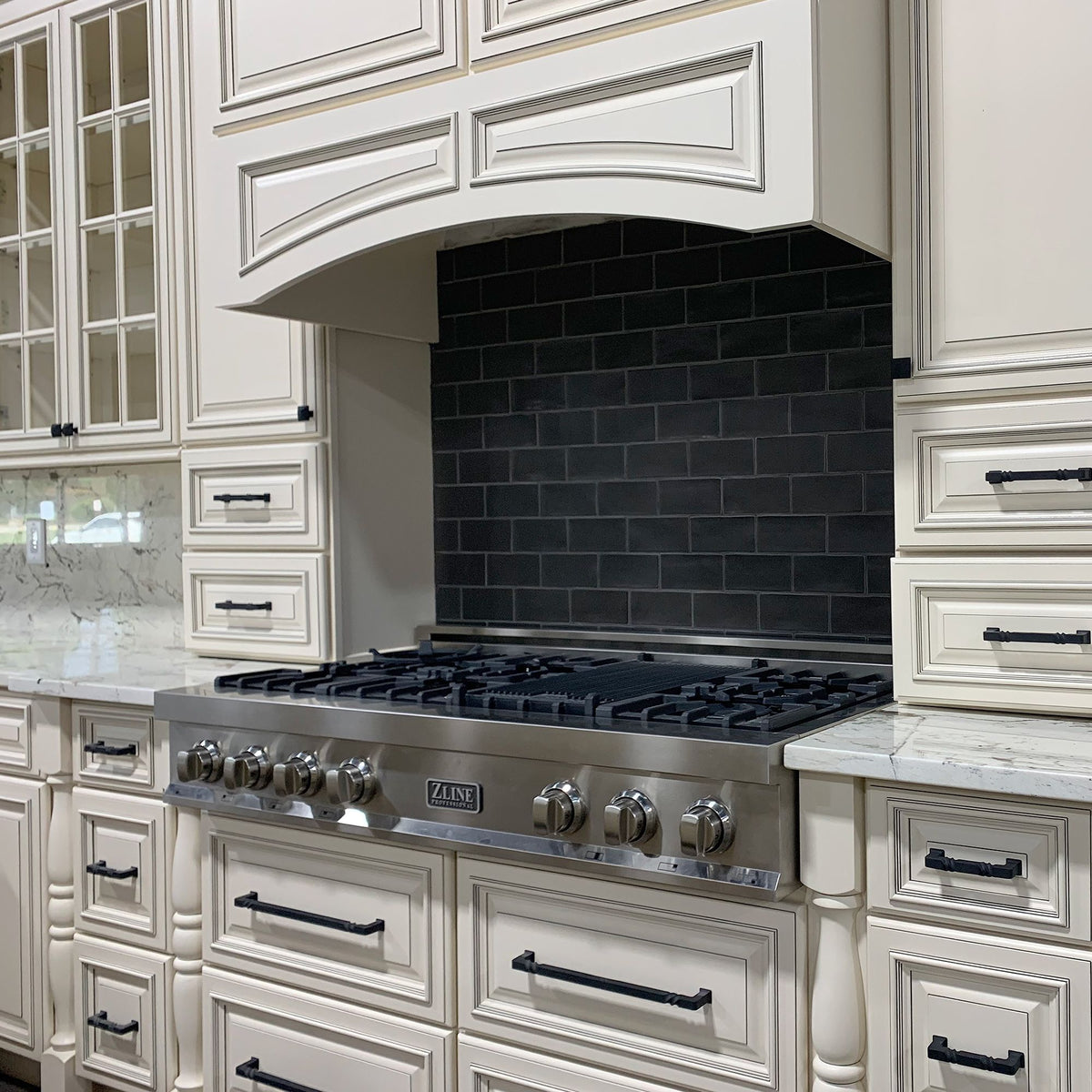 Stainless gas range with multiple burners and front control knobs in kitchen cabinetry