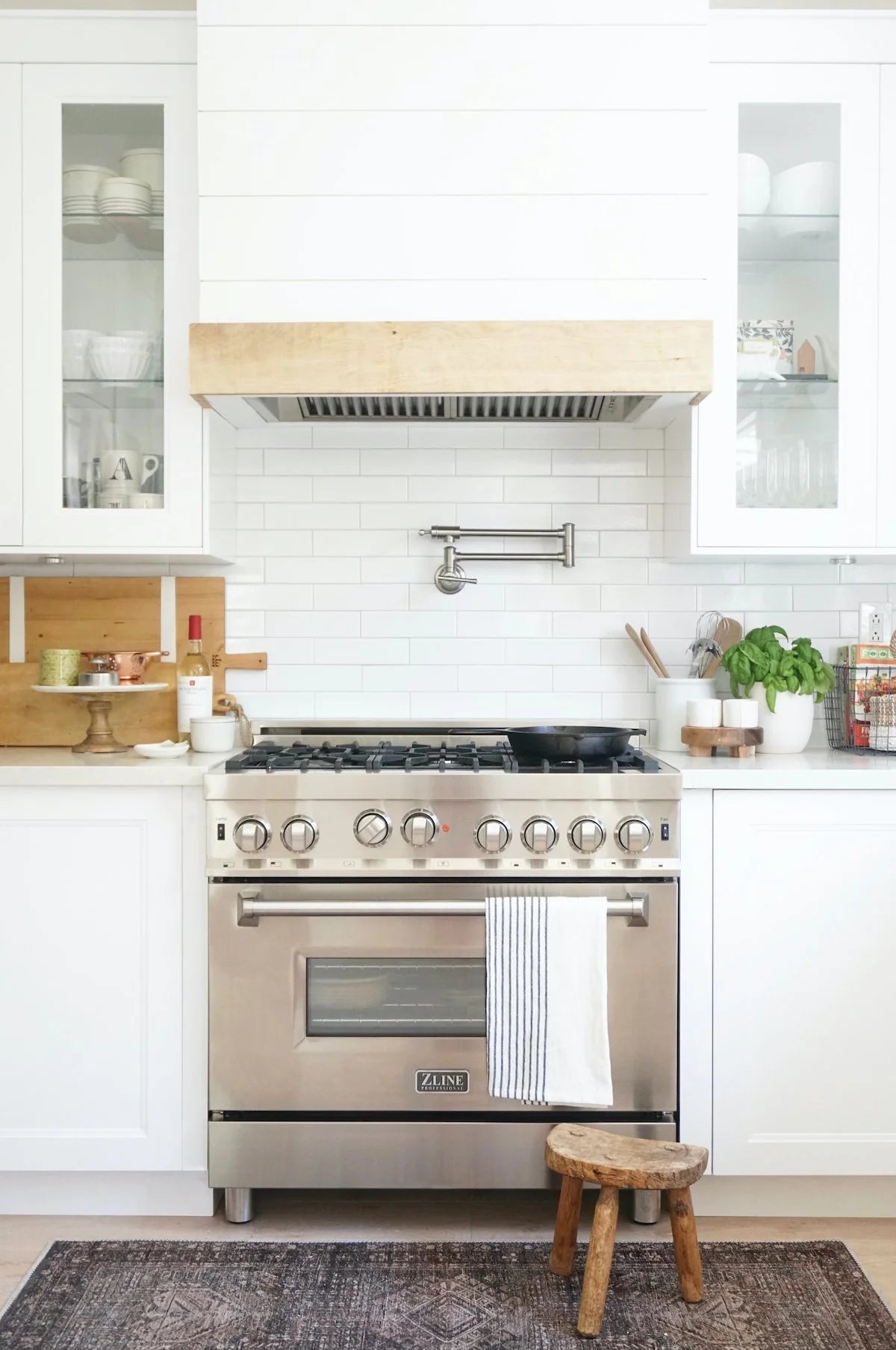 Stainless steel range hood insert above a gas range in a kitchen setting