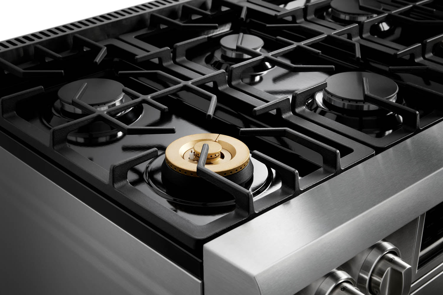 Gas burner cap close-up on stainless steel cooktop with black grates