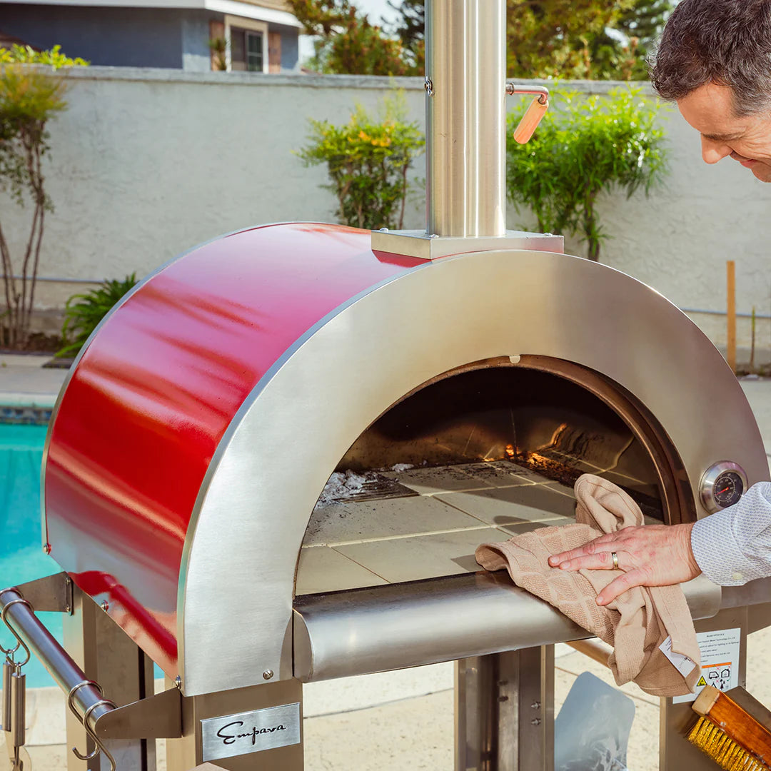 Wood fired pizza oven mouth with stainless arched door and pizza peel loading dough