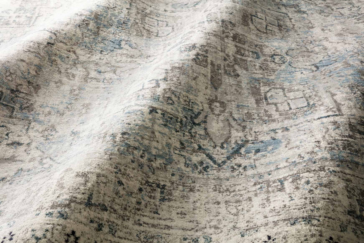 Textured area rug close-up with mottled light gray base and blue abstract marks
