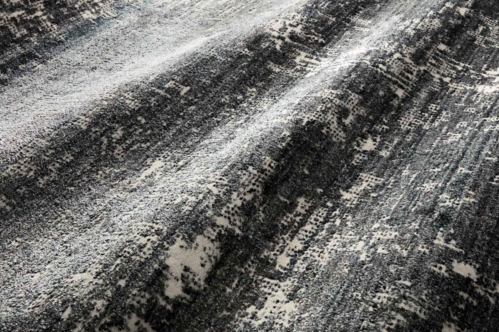 Denim blue and light gray abstract rug with dense textured speckling, diagonal view