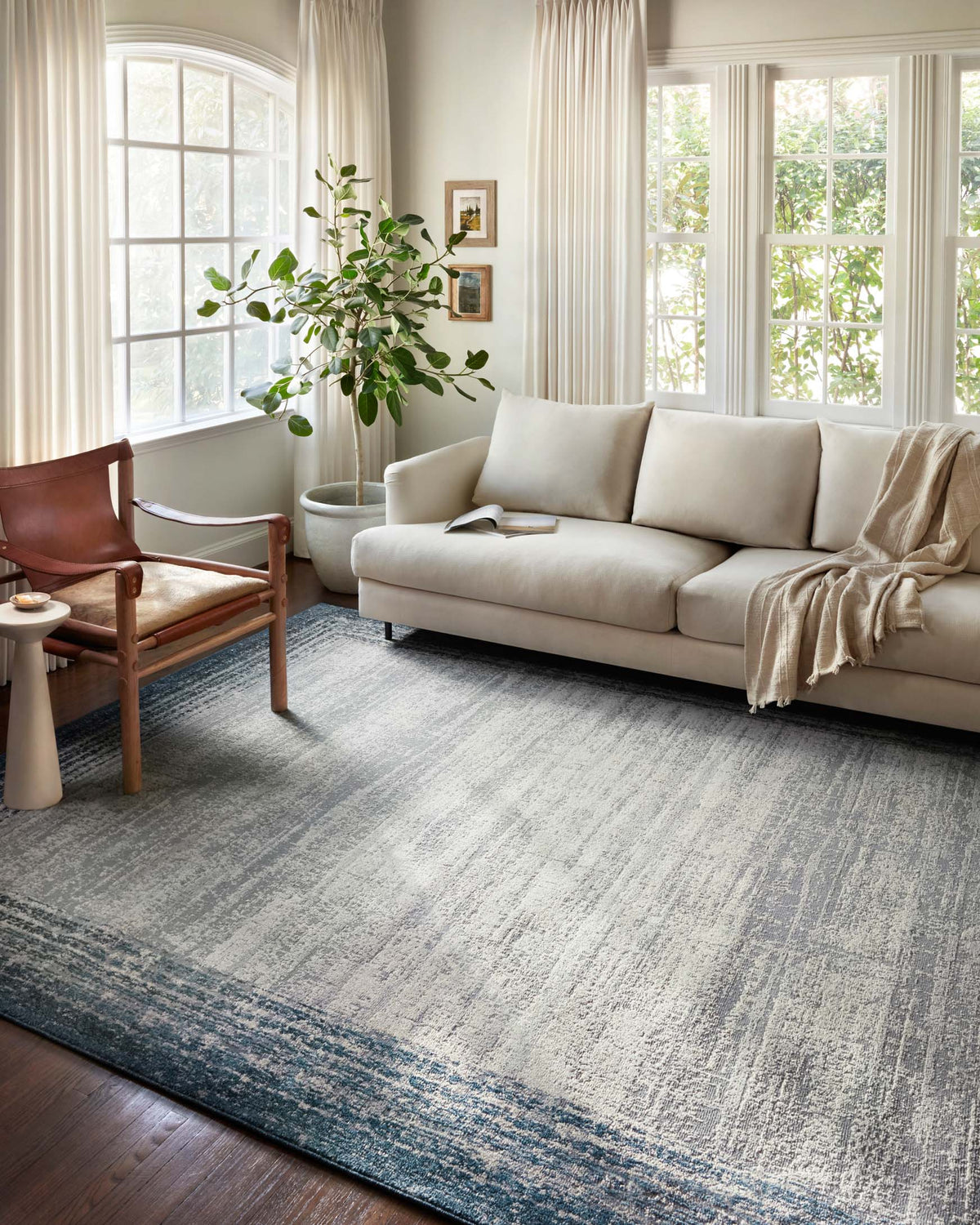 Pebble-and-blue abstract bordered area rug with distressed texture, low pile