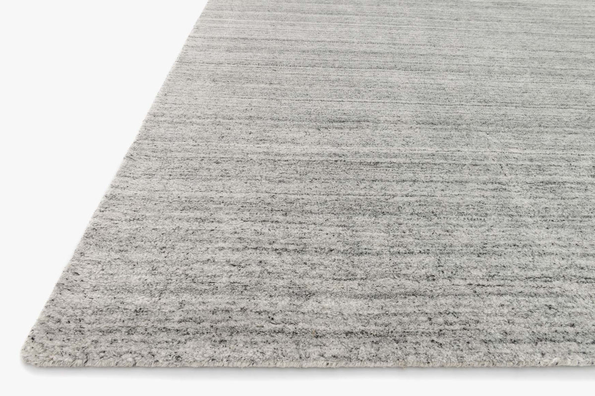 Silver hand-loomed area rug corner with short, dense pile and linear texture.