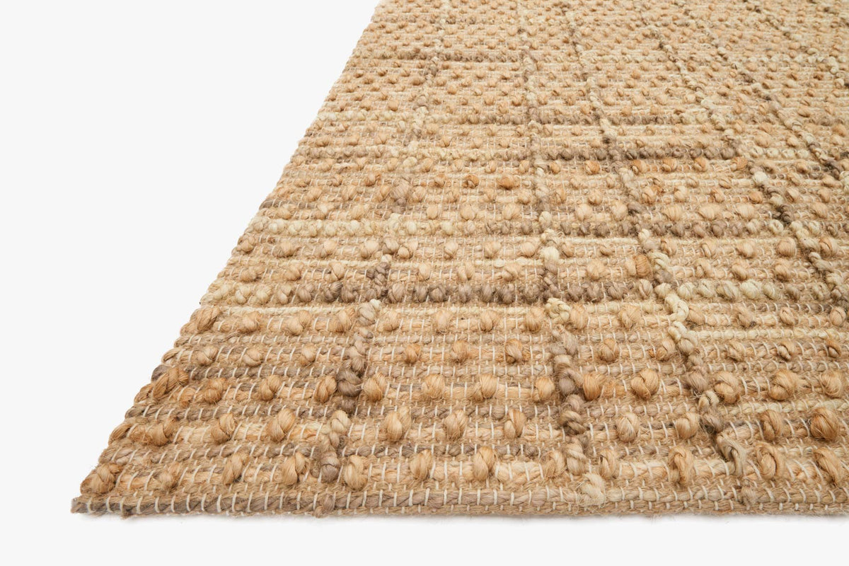 Natural hand-woven rug corner detail with looped texture and frayed fringe edge.