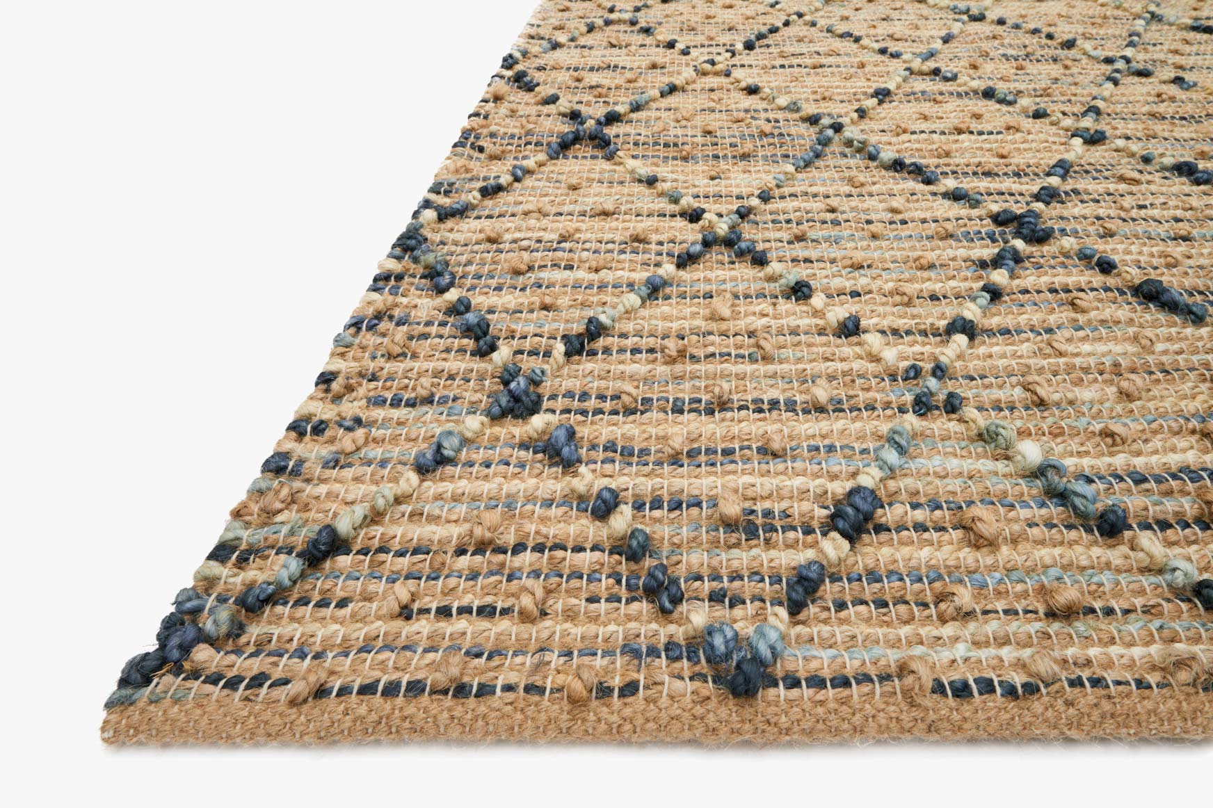 Hand-woven rug corner detail with navy knot accents on beige textured surface