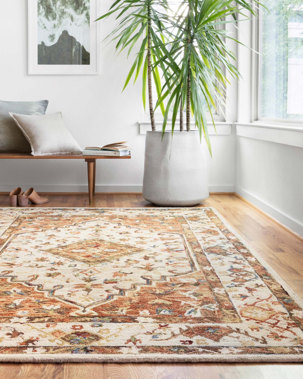 Traditional hooked rug with distressed geometric border in ivory and rust tones.