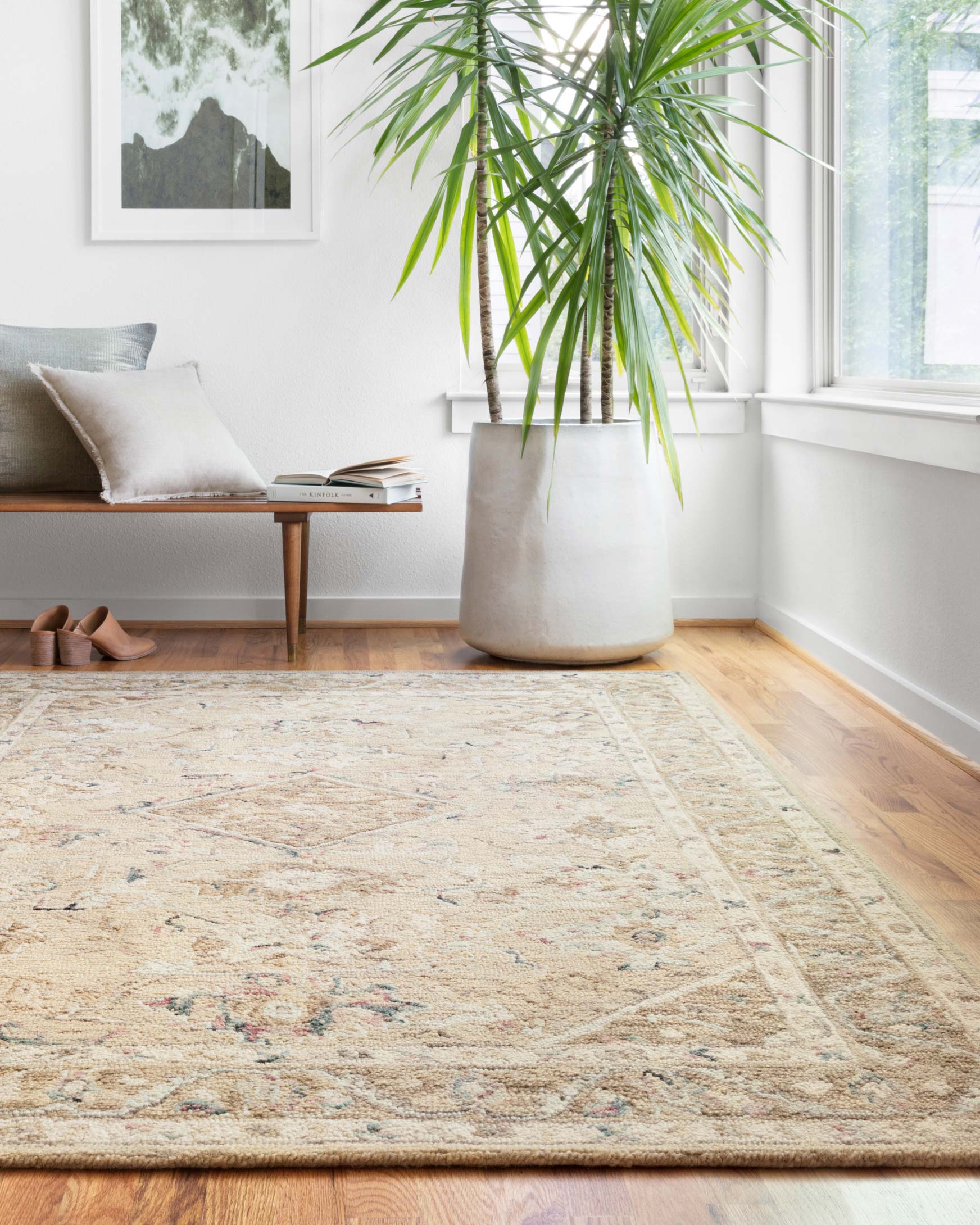 Beige and ivory traditional hooked rug with faded blue, green, and pink patterning.