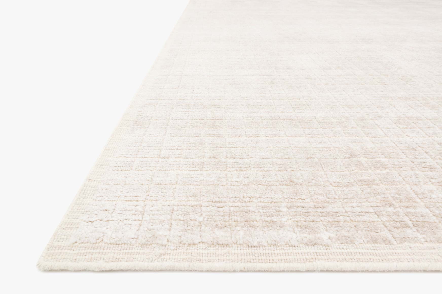 Natural hand-loomed rug corner with low-pile grid texture and stitched border edge