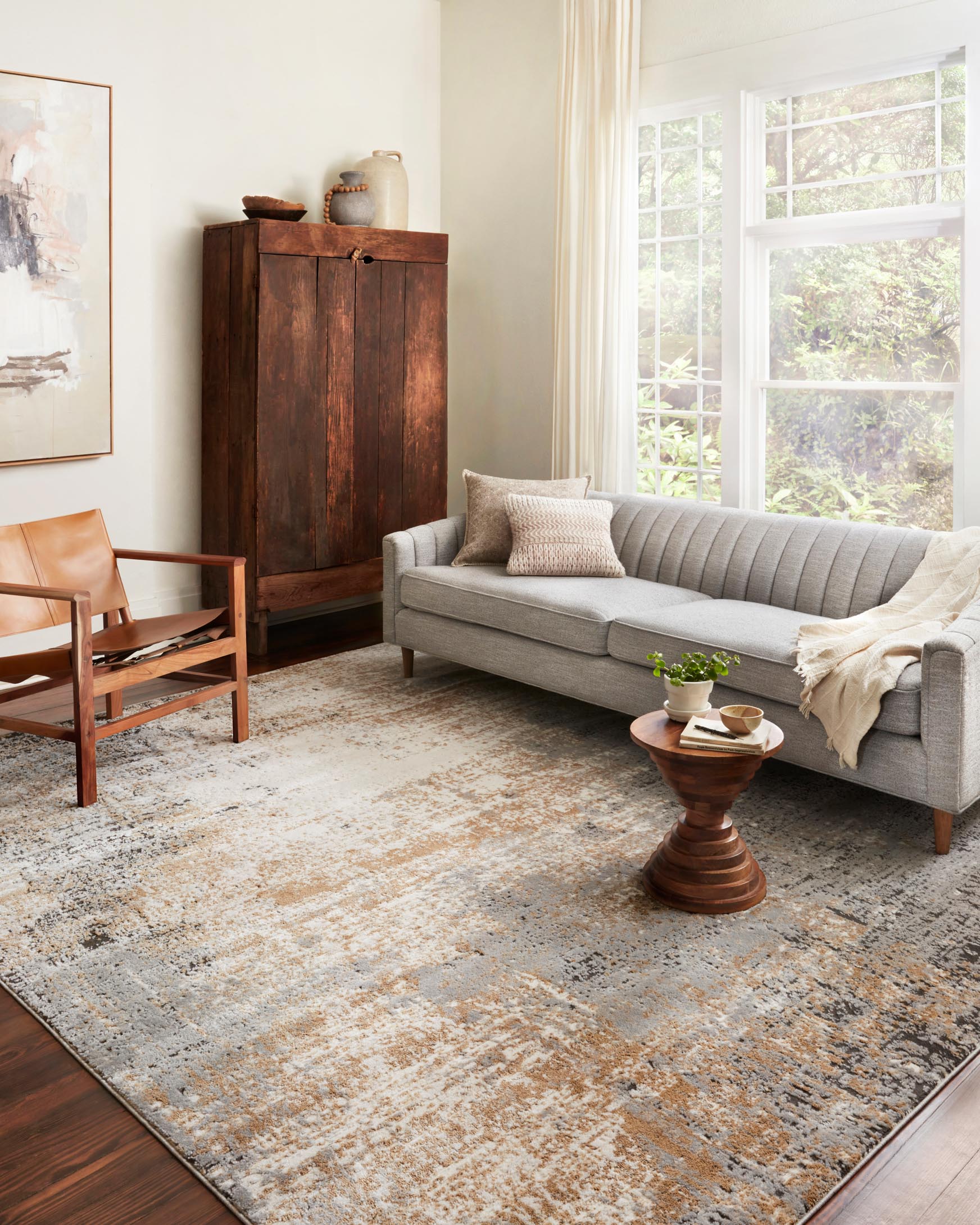 Abstract area rug in stone and gold with dark speckles, shown on a hardwood floor