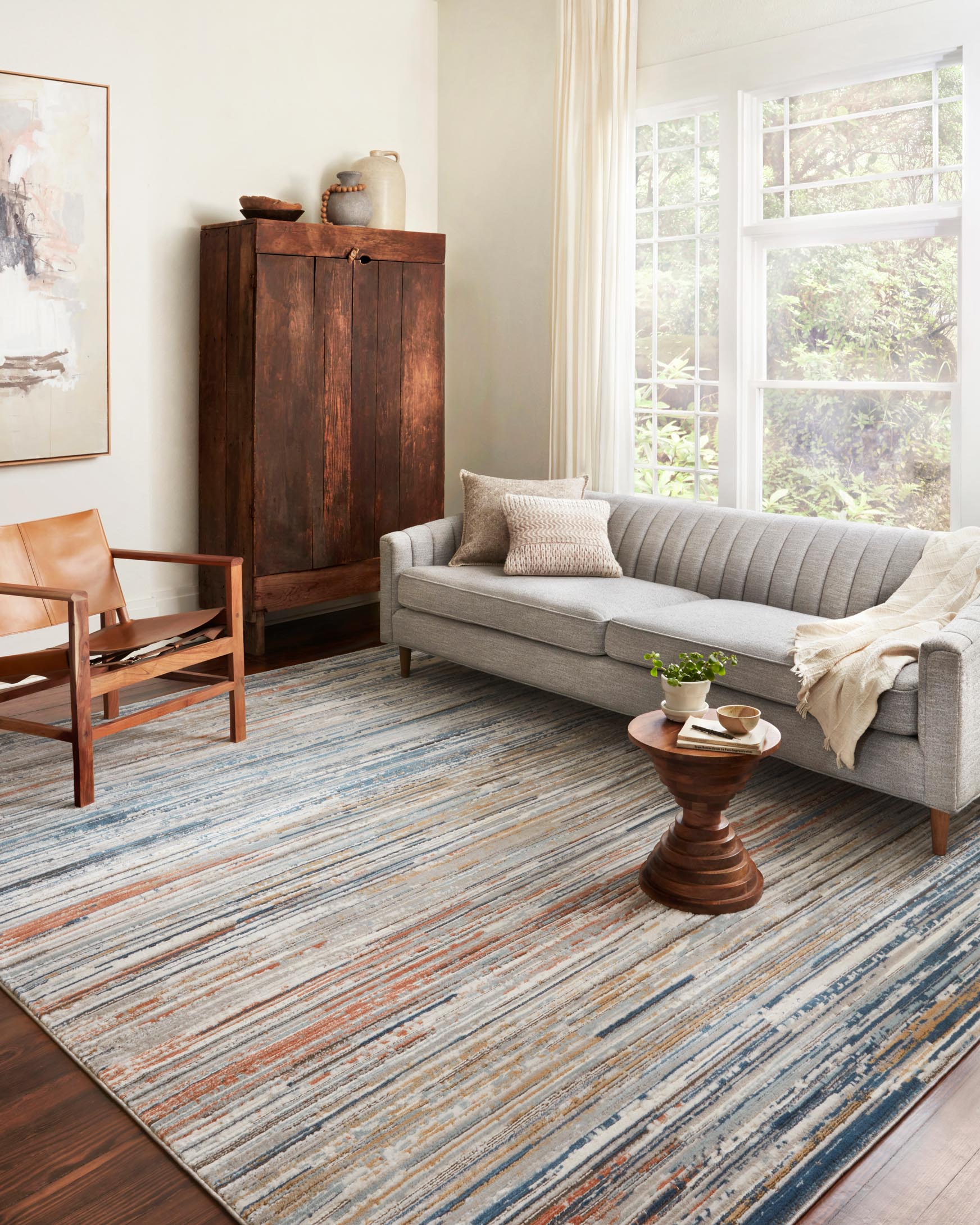 Contemporary rug with blue, tan, and rust horizontal stripes on a light pebble base