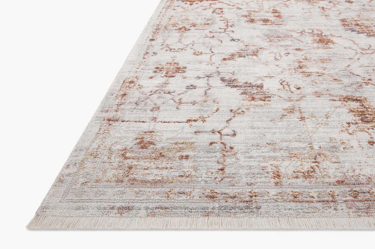 Traditional power-loomed rug corner with short fringe and rust geometric pattern on ivory