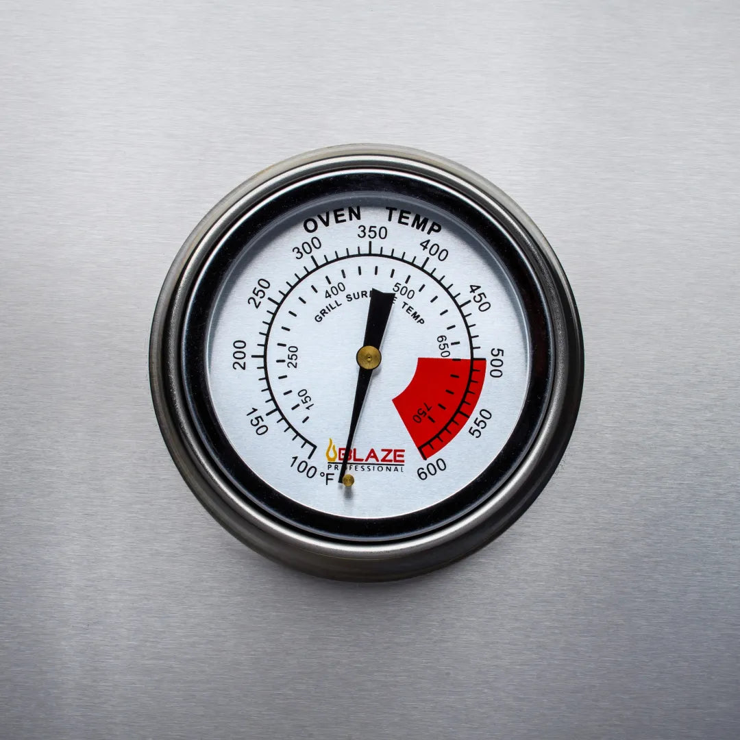 Oven temperature gauge on stainless grill lid with red and black indicator markings