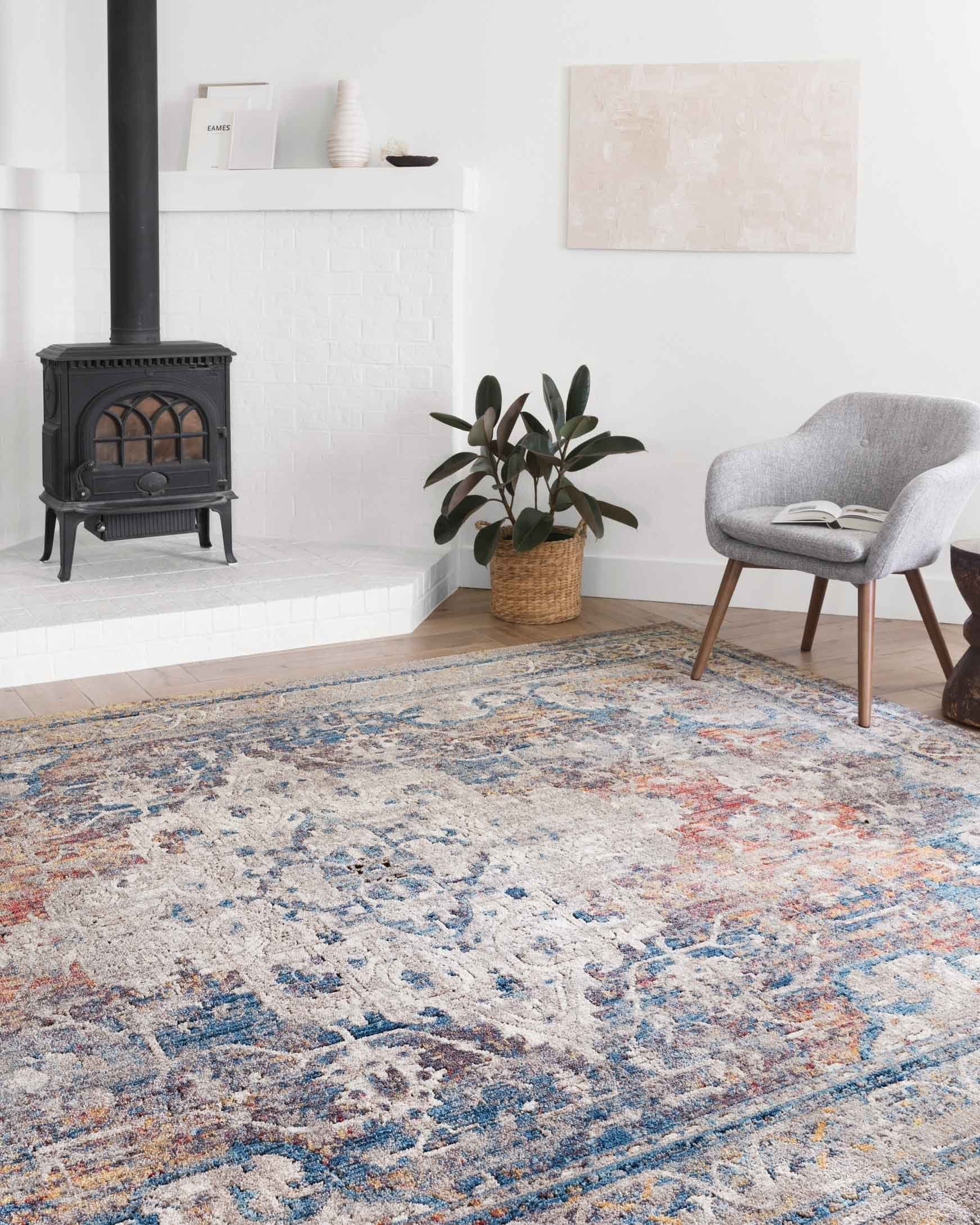 Transitional rug with distressed blue and stone motif, orange flecks, and decorative border.
