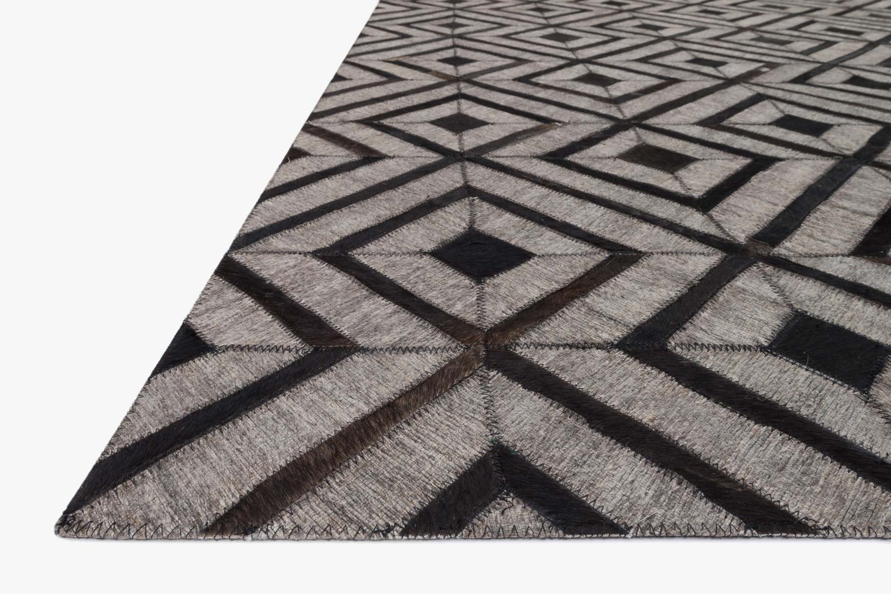 Corner view of beige and dark brown rug with bold geometric sunburst diamond pattern