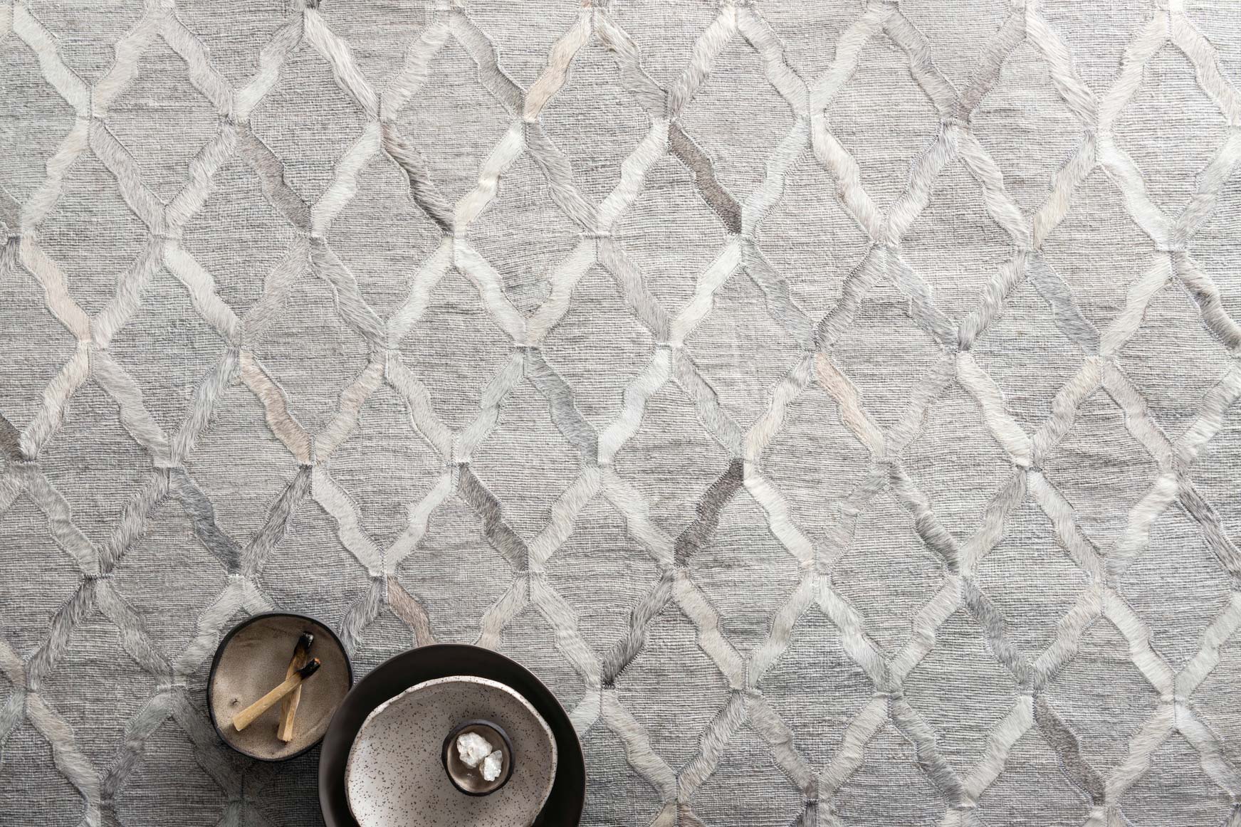 Light grey geometric diamond pattern rug, textured woven surface close-up