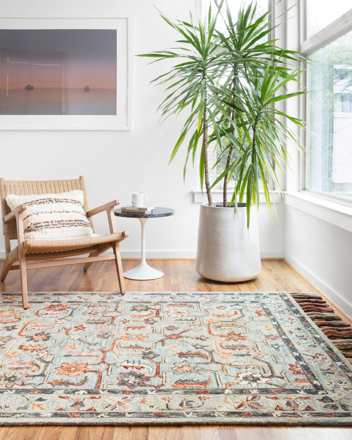 Transitional hooked rug in sky blue with colorful geometric border and tassel fringe