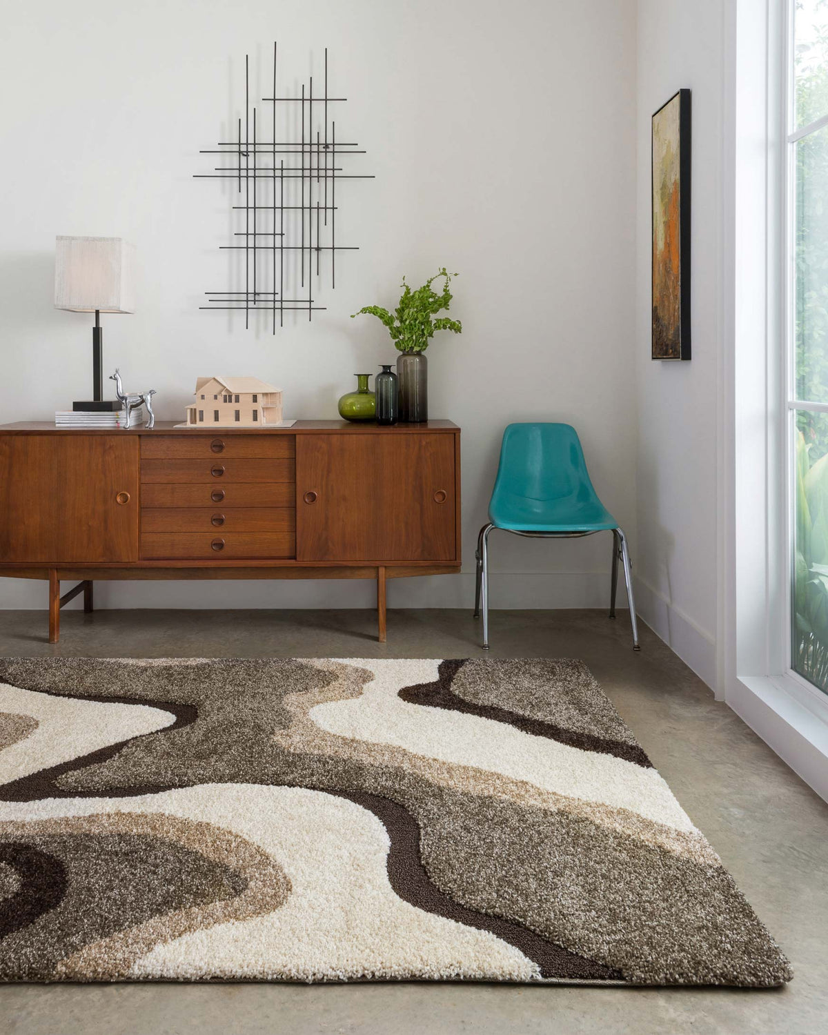 Abstract area rug in beige, tan, and charcoal with large wavy shapes and soft texture.