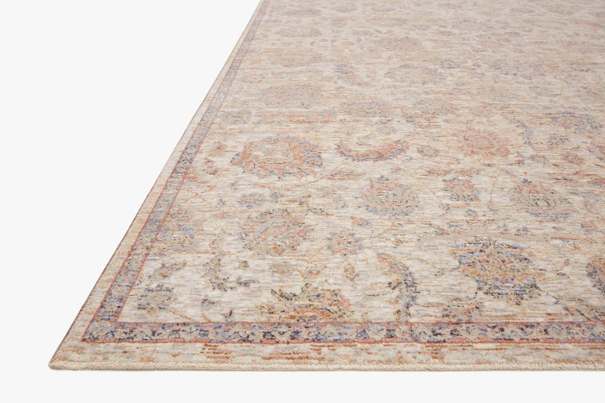 Angled view of beige power-loomed rug with faded multicolor motif and striped edge