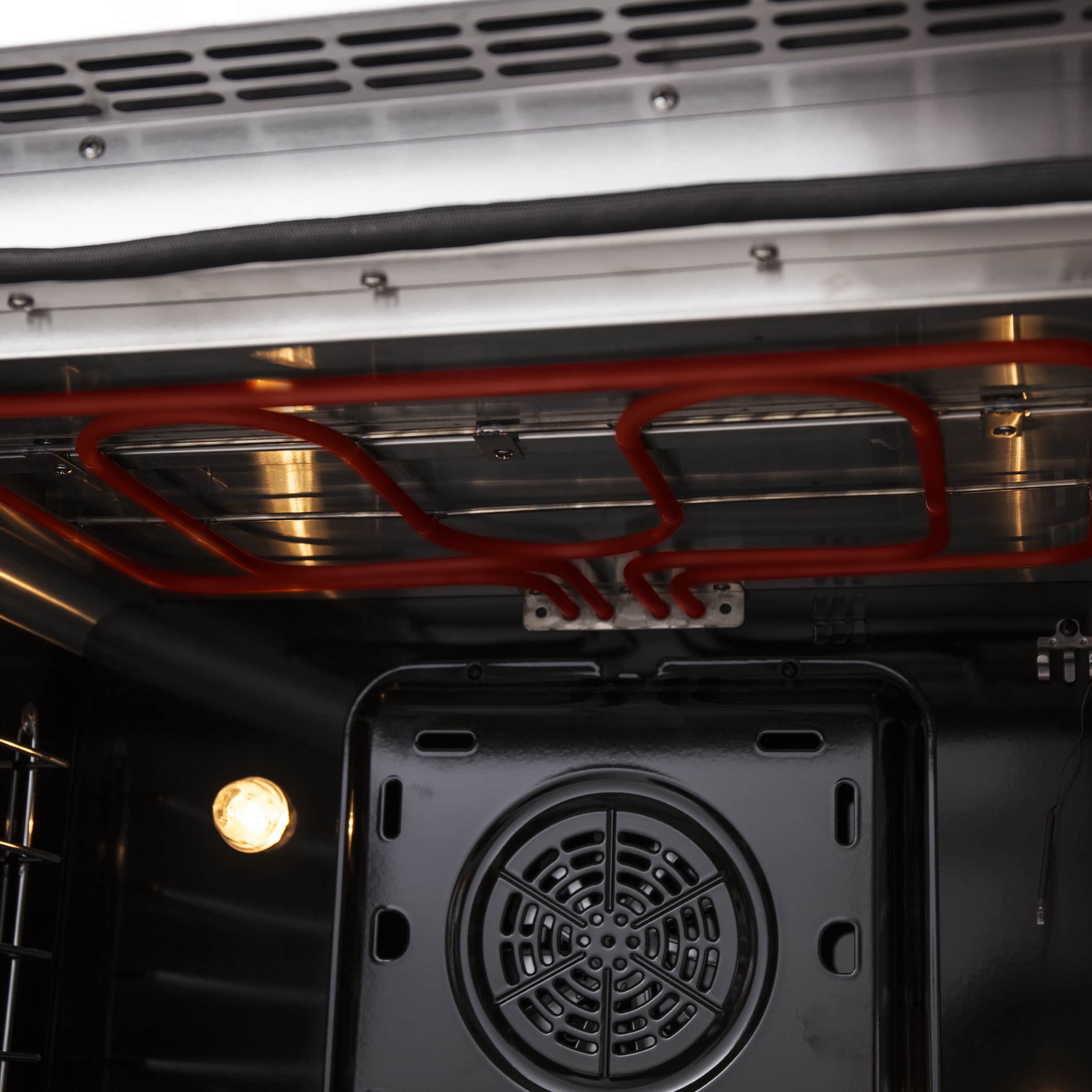 Dual fuel range oven heating elements with red glow above the fan vent