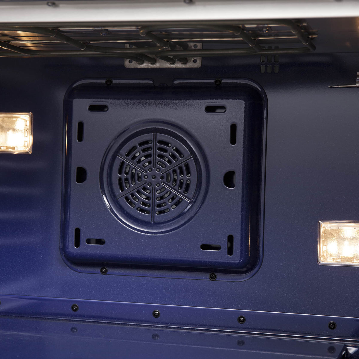 Oven interior close-up of circular convection fan vent with corner mounting holes
