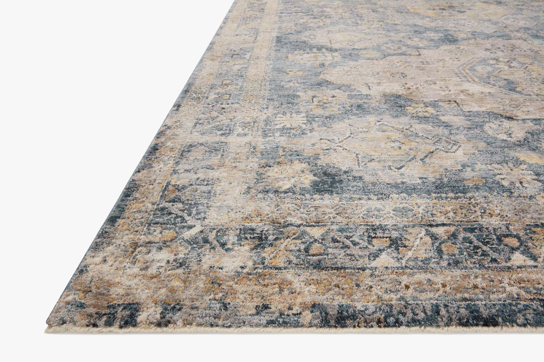 Corner view of transitional rug with distressed geometric pattern in denim blue and taupe.