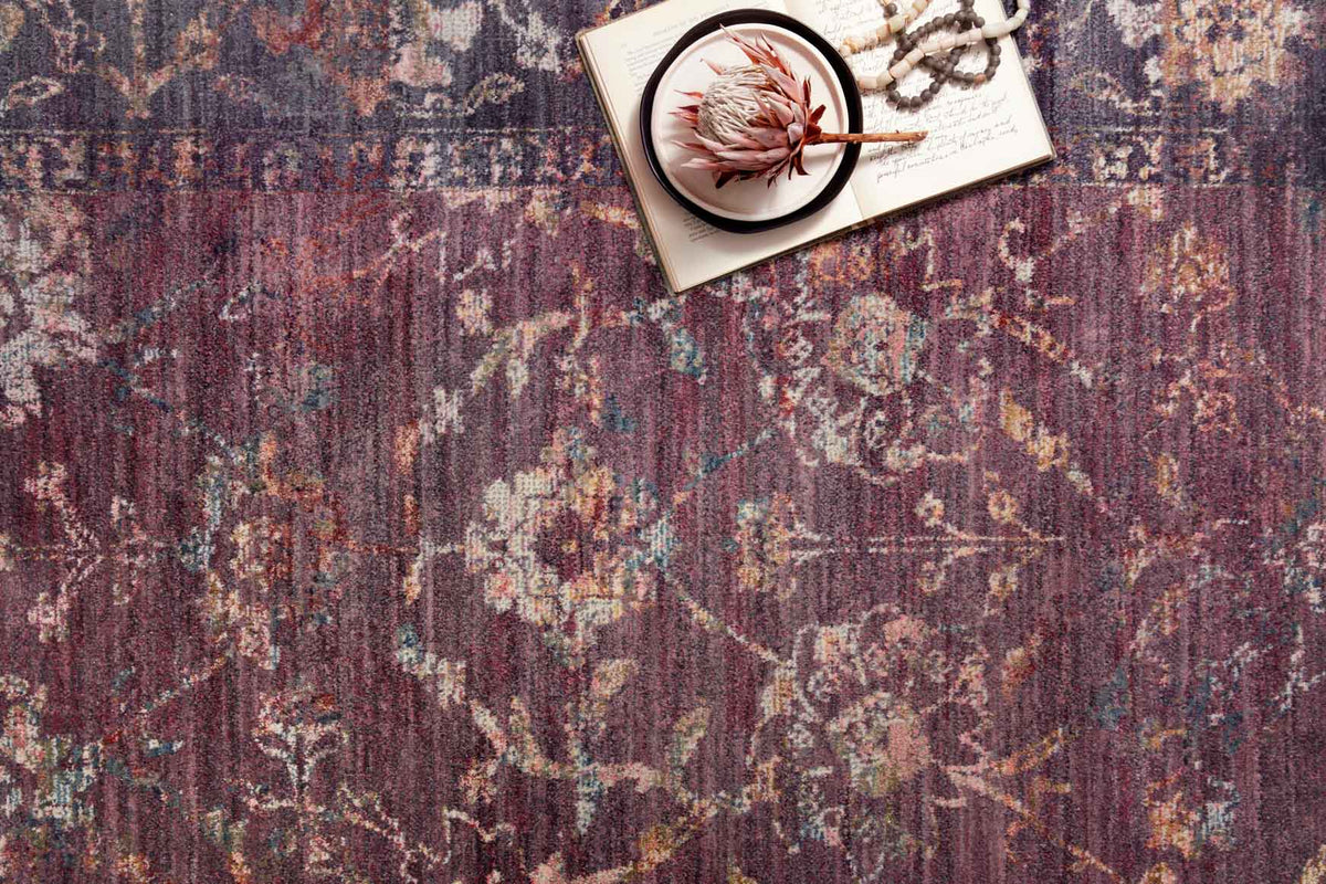 Traditional power-loomed rug surface with textured multicolor abstract pattern in grape tones.