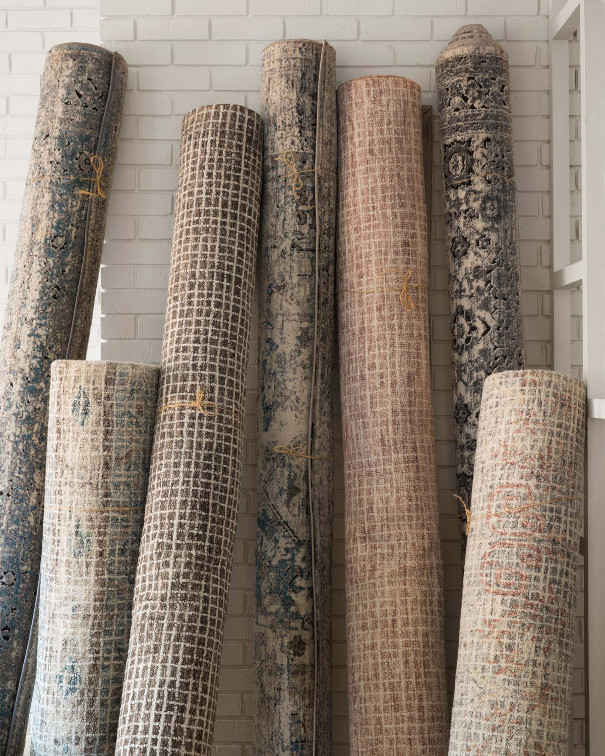 Blush hooked rug shown rolled on its side, with textured woven surface