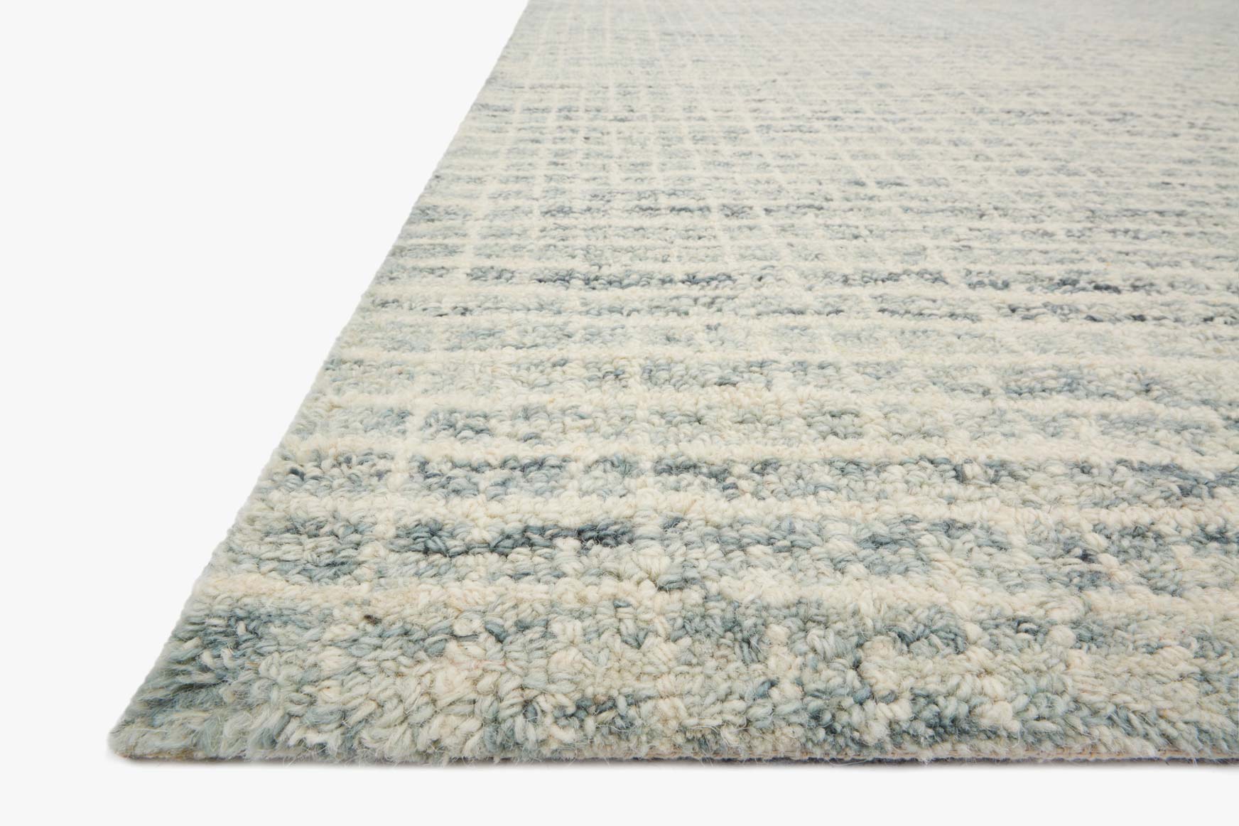 Transitional hooked rug with textured light blue and cream pile, angled view of corner