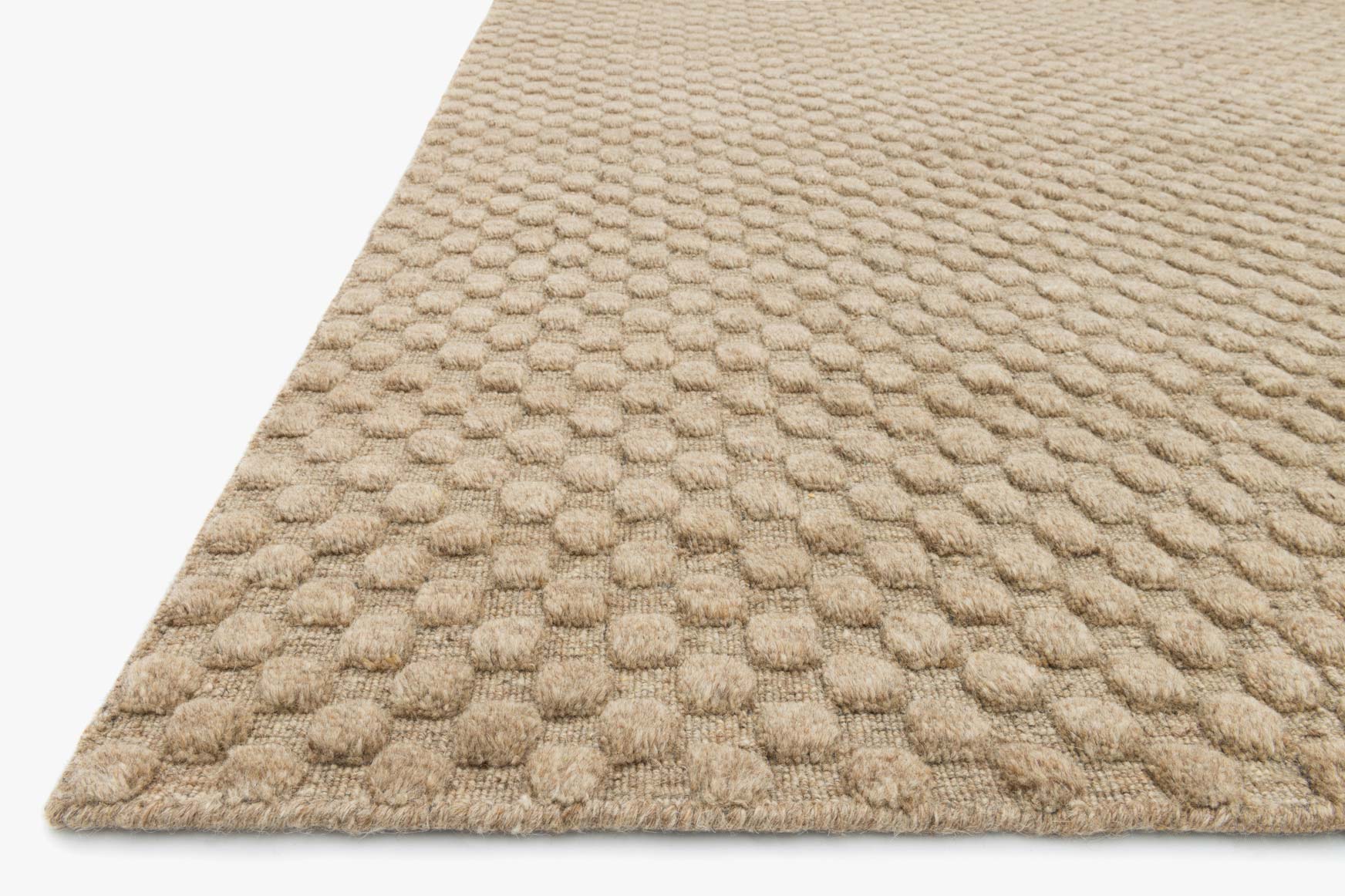 Corner view of hand-loomed rug with raised looped pebble texture, light tan