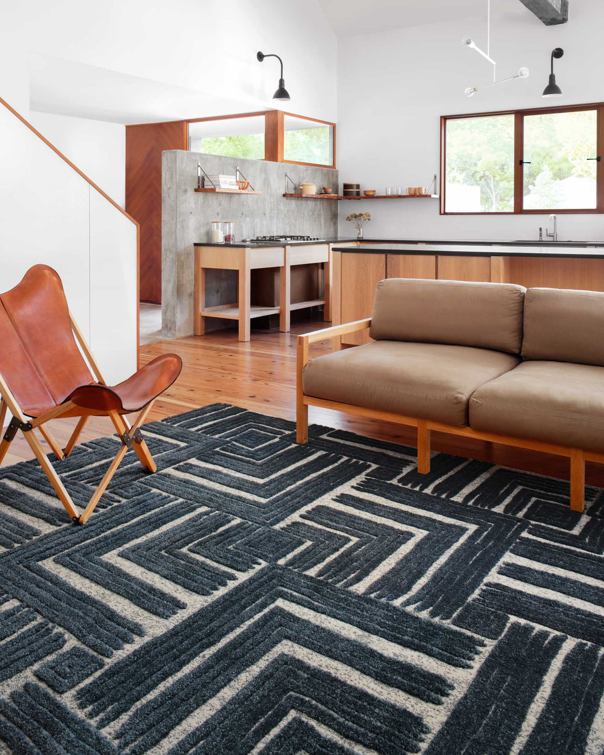 Blue and white geometric rug with bold chevron blocks, shown under living room seating