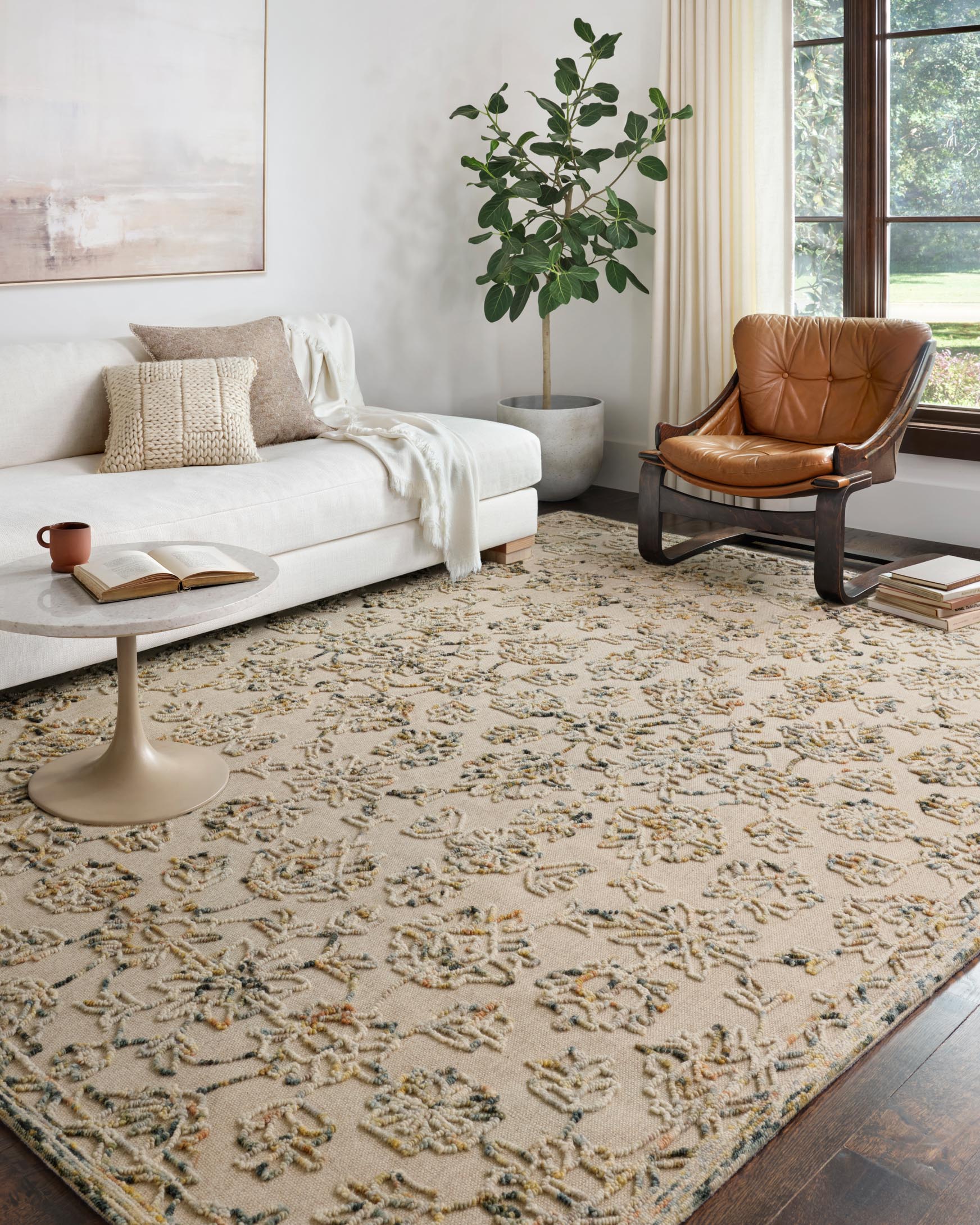 Traditional hooked area rug in light beige with ornate blue-green and tan floral pattern
