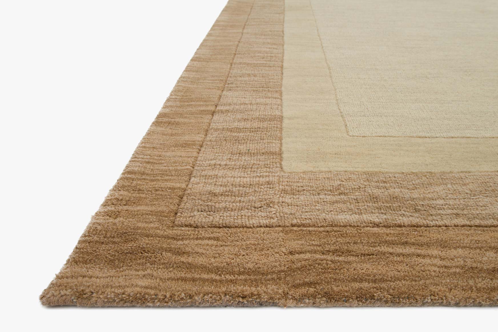 Beige hand-loomed rug corner with layered border and low pile texture.