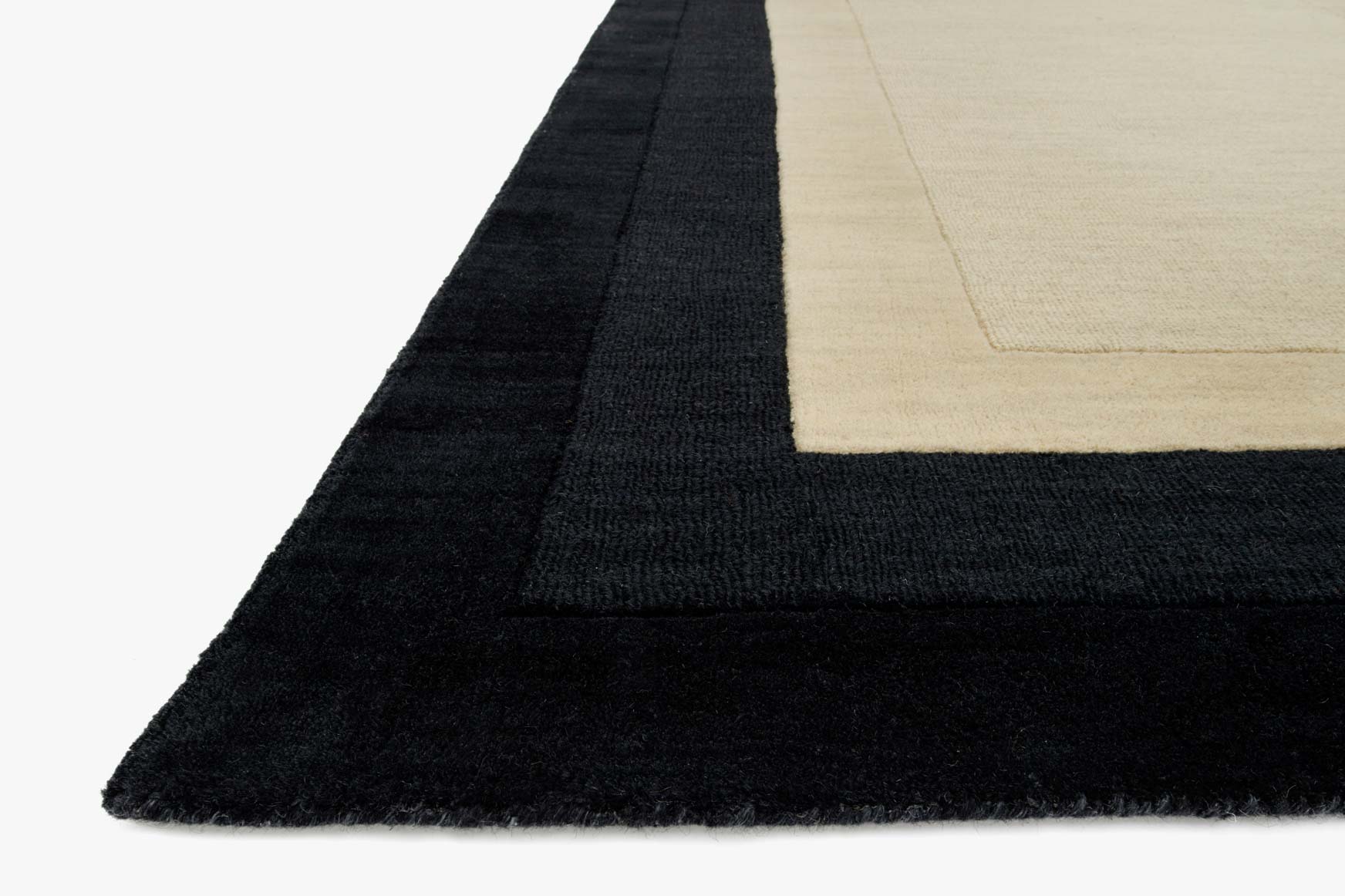 Corner view of hand-loomed rug: charcoal edge with ivory panel and stitched border