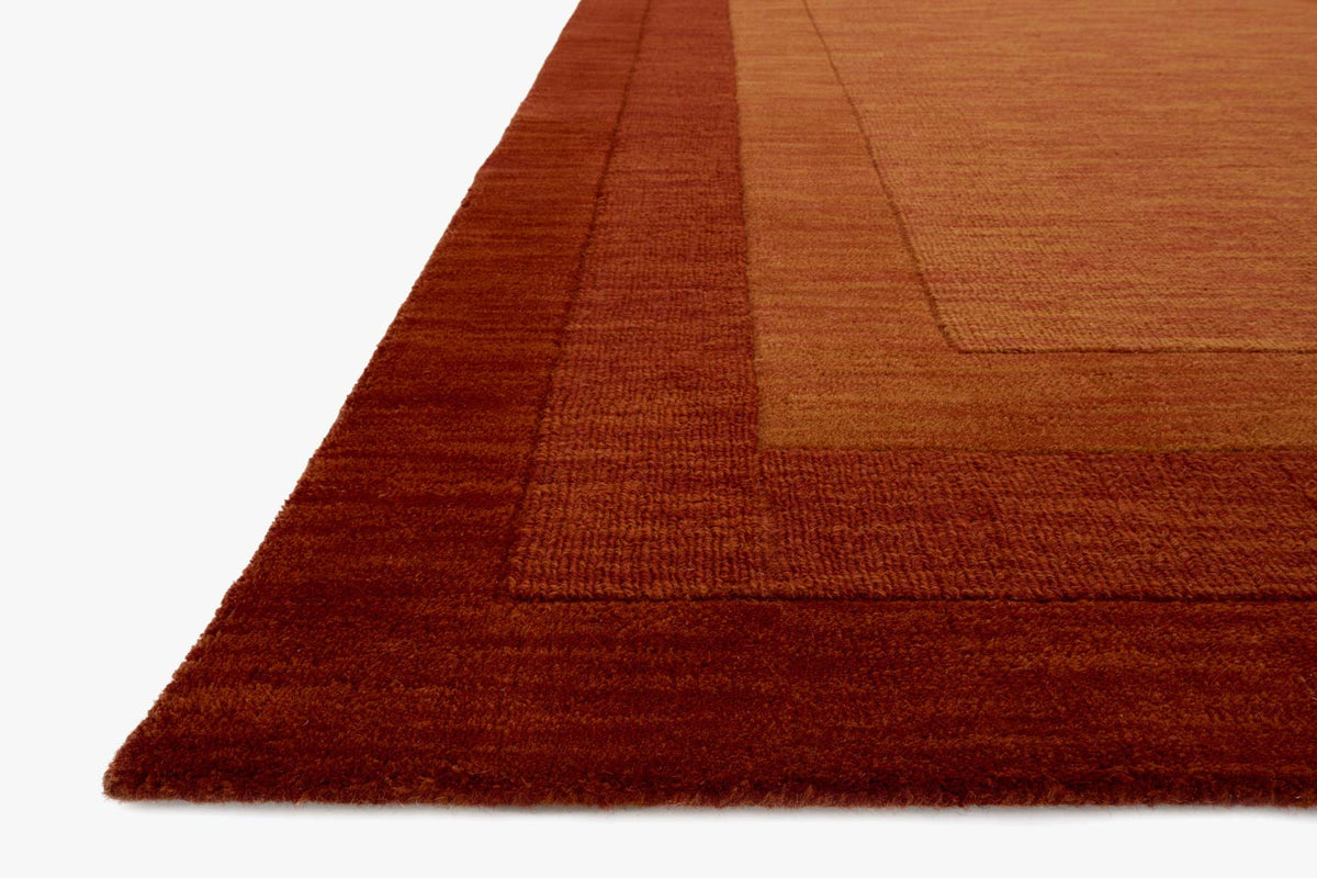 Rust hand-loomed rug corner close-up with textured weave and flat border