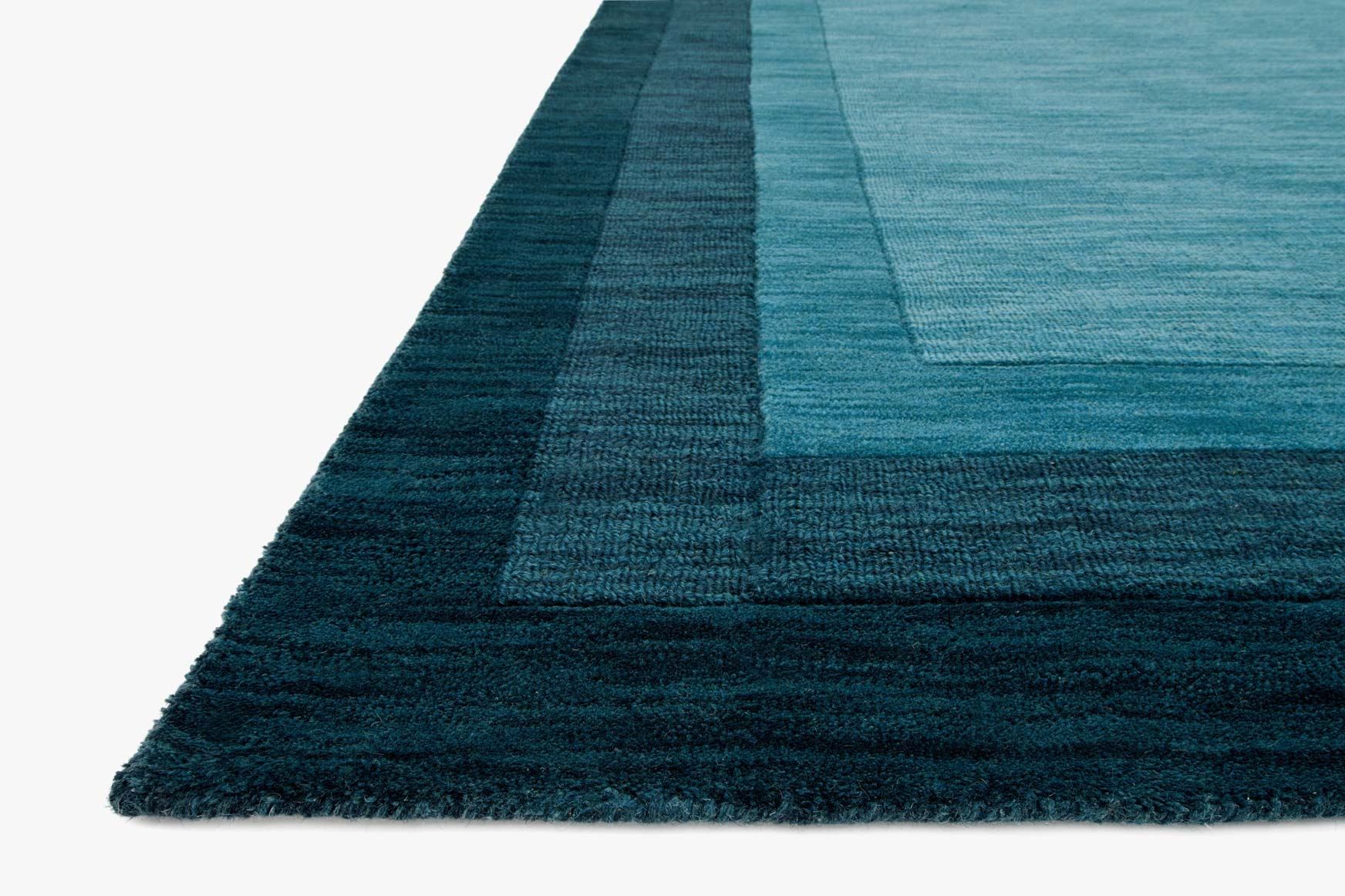 Teal hand-loomed rug corner with dense pile and tonal border