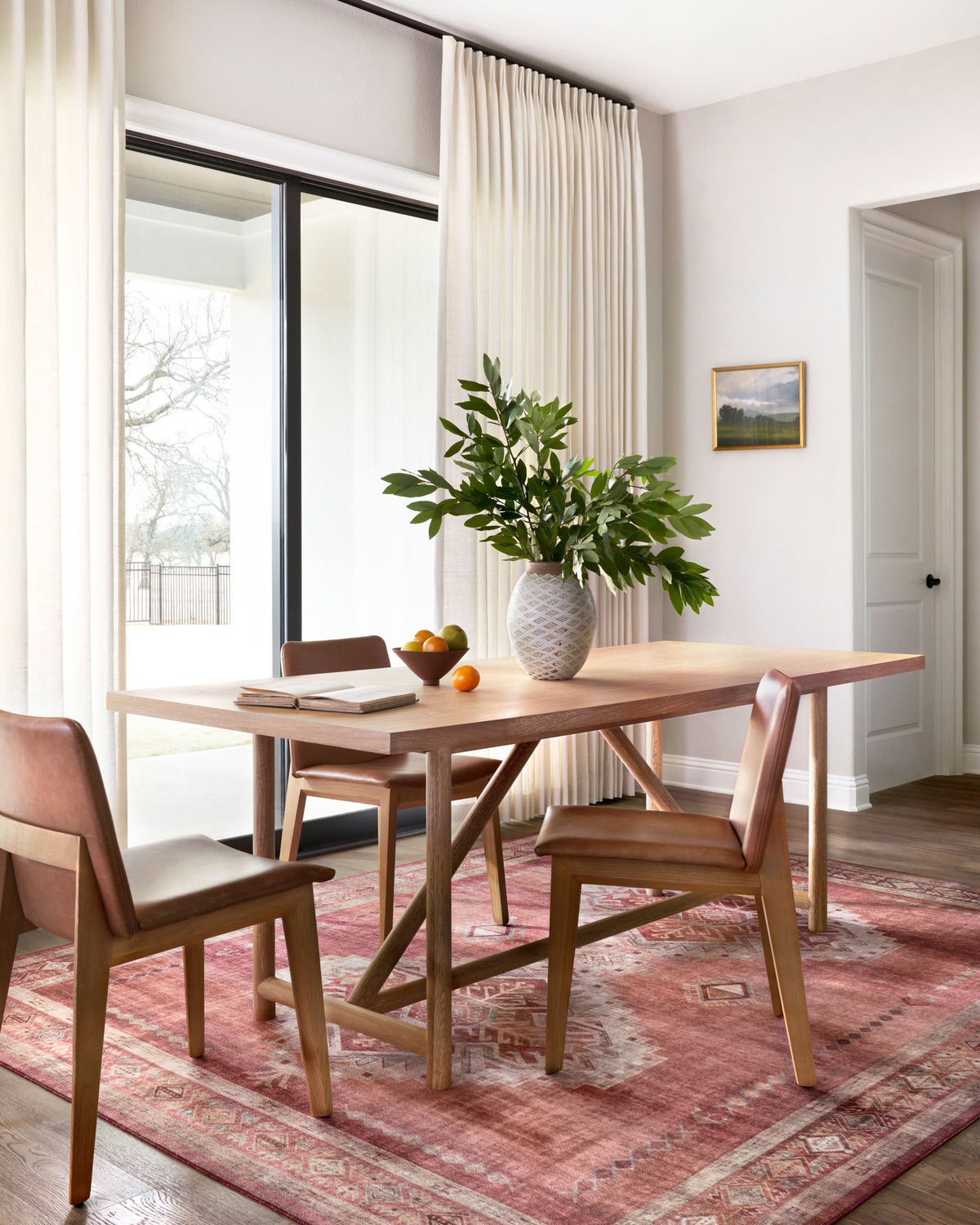 Geometric patterned area rug in rust red and ivory beneath a dining table.