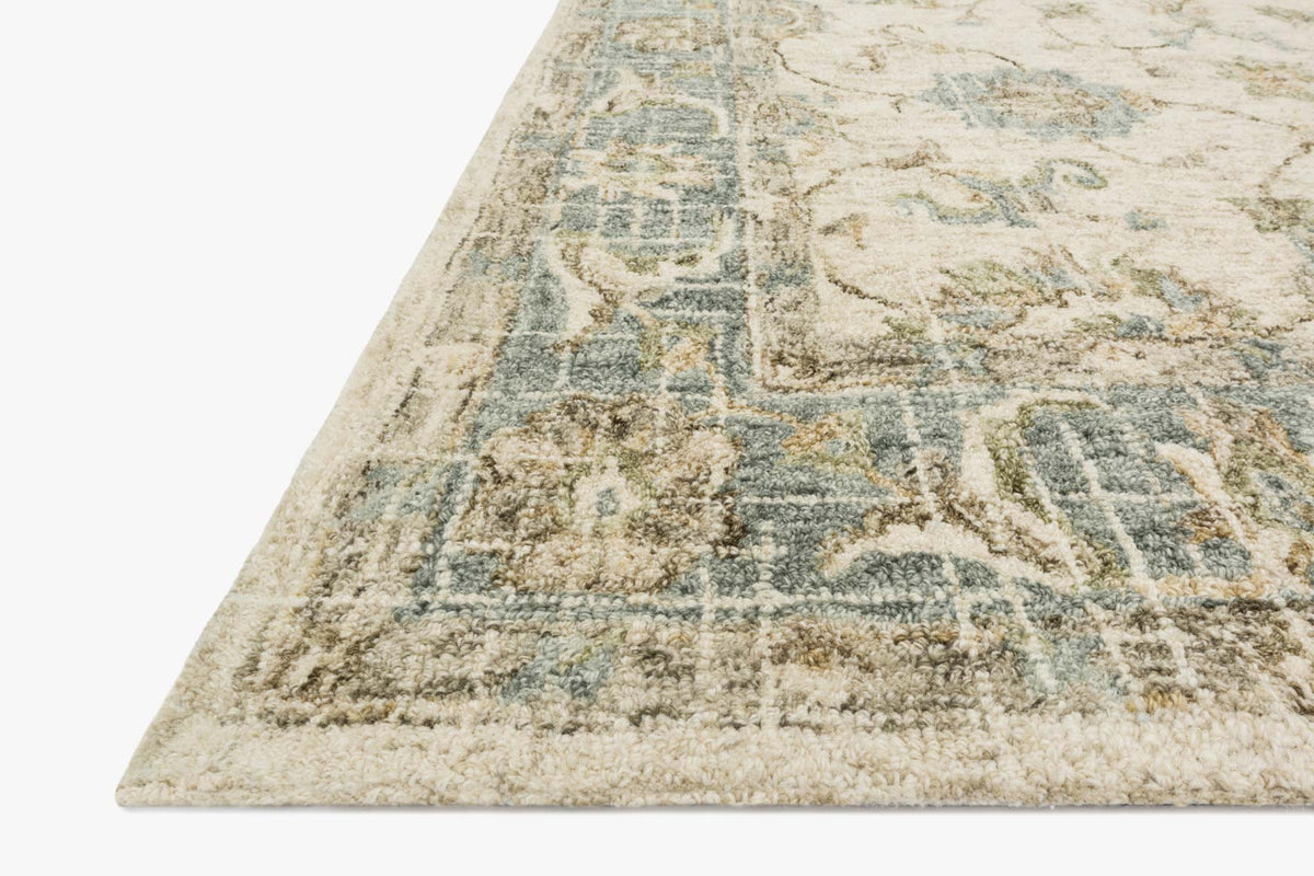 Corner view of ivory and spa hooked rug with abstract floral pattern and textured pile