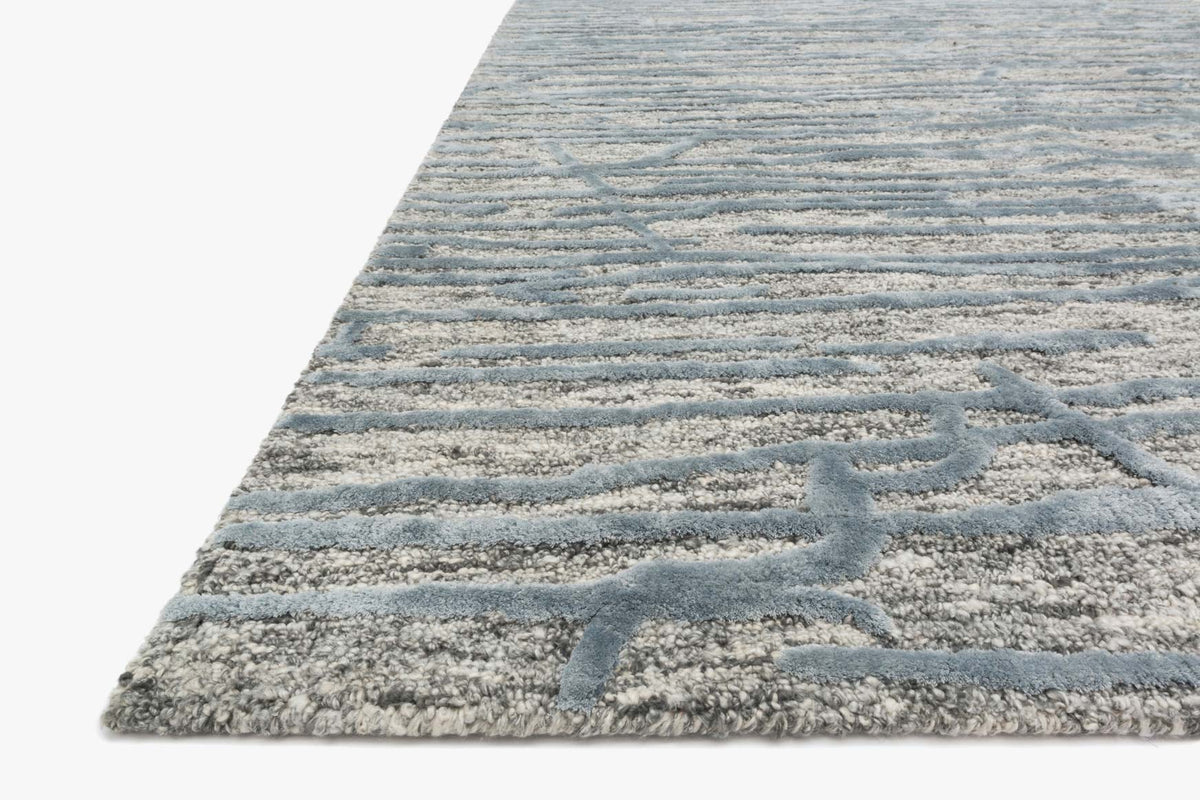 Hand-tufted area rug corner in grey and blue with geometric motif and textured pile