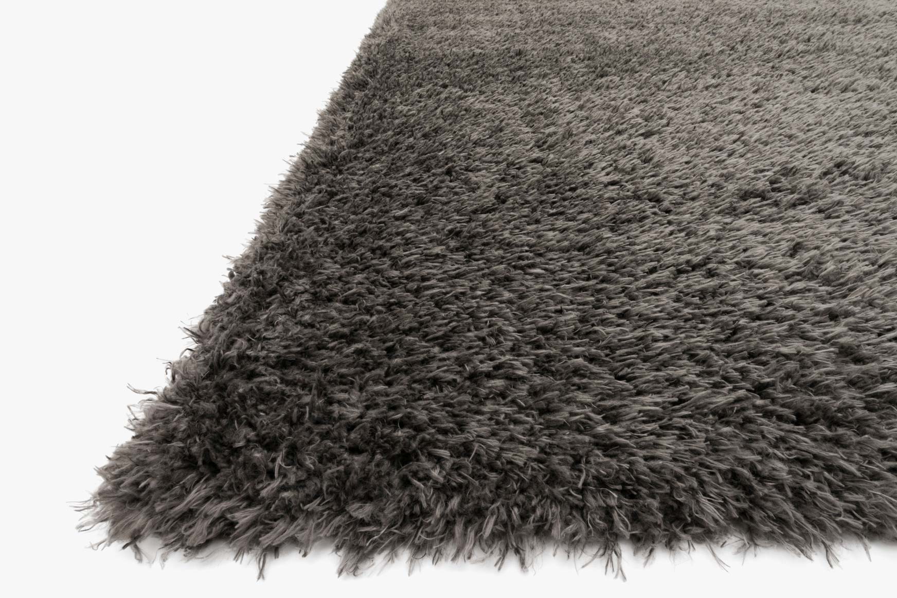 Grey shag rug corner close-up showing thick, fluffy pile fibers and overhanging edge