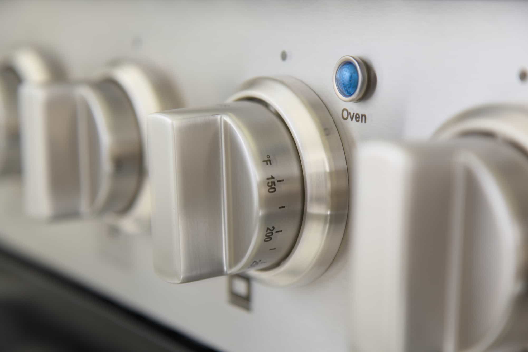 Stainless oven control knob with temperature markings next to blue indicator