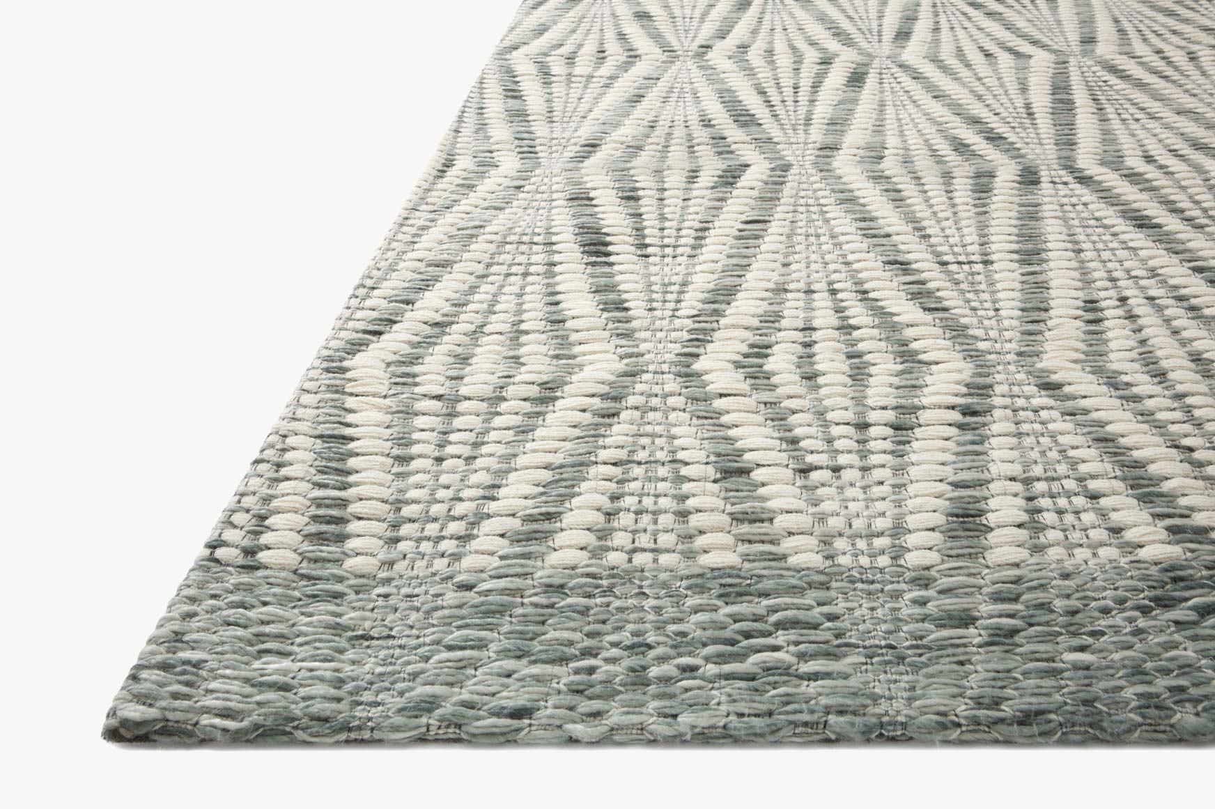 Hand-woven area rug corner in ivory and sage with textured geometric lozenge pattern.