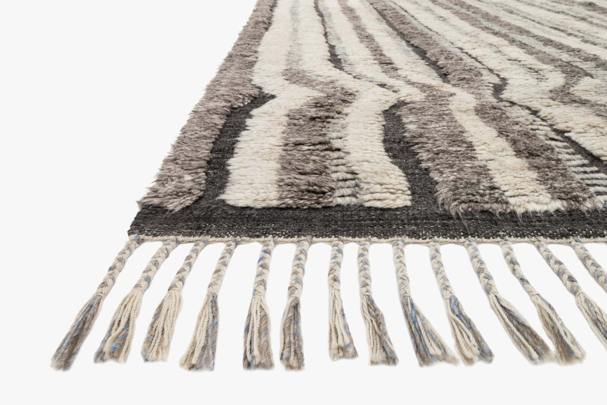 Hand-knotted rug corner with charcoal and stone geometric pattern and long tassel fringe