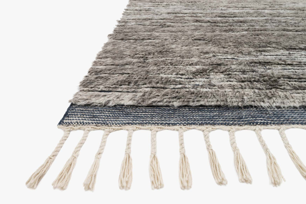 Hand-knotted area rug with gray texture, blue border, and white fringe