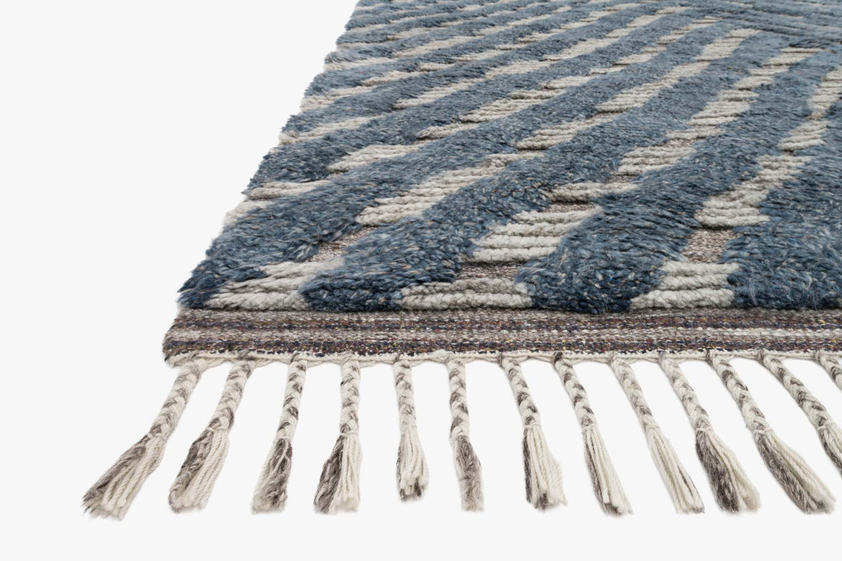 Blue and pewter hand-knotted rug corner with chevron texture and hanging fringe