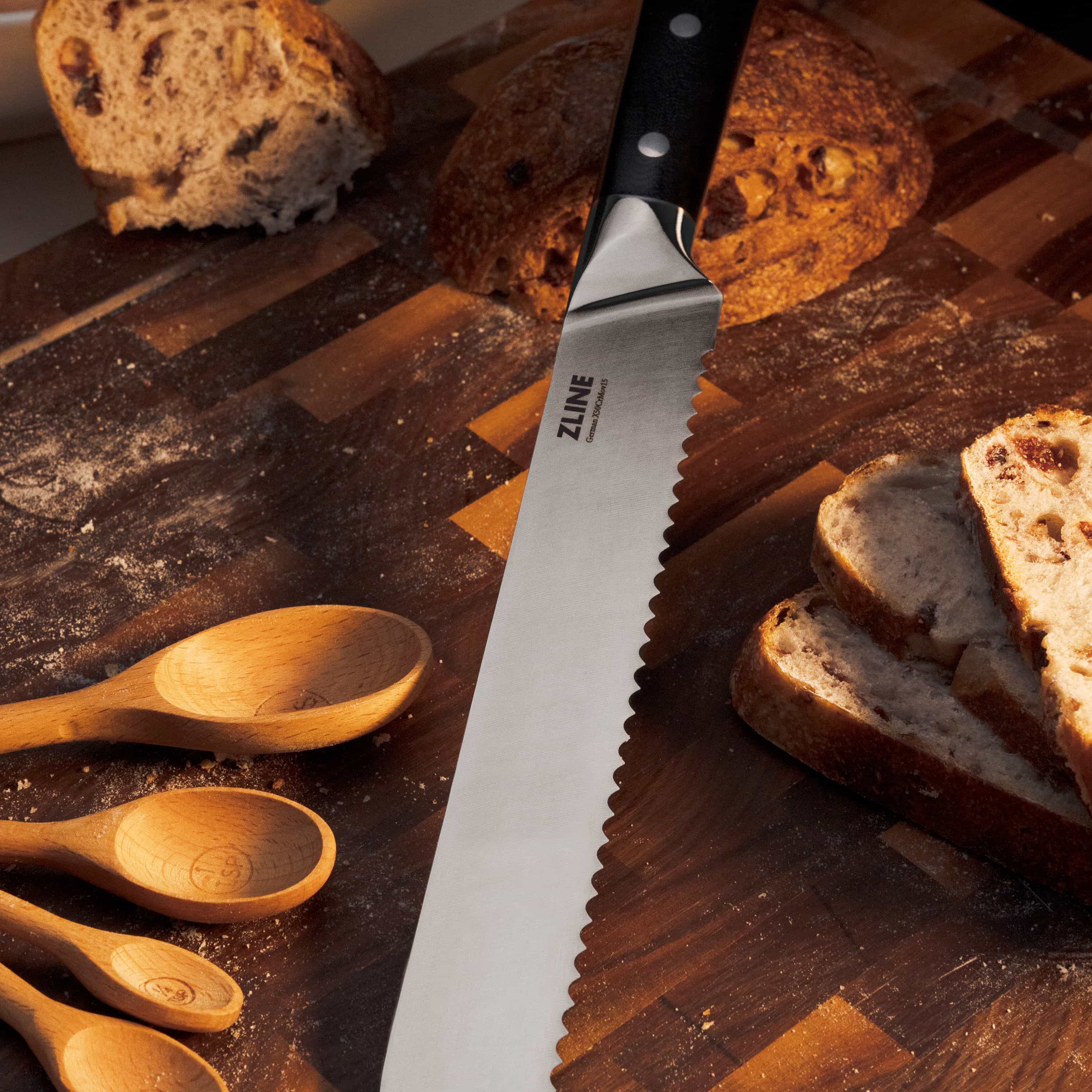 Stainless serrated knife with black handle beside sliced bread on wooden board