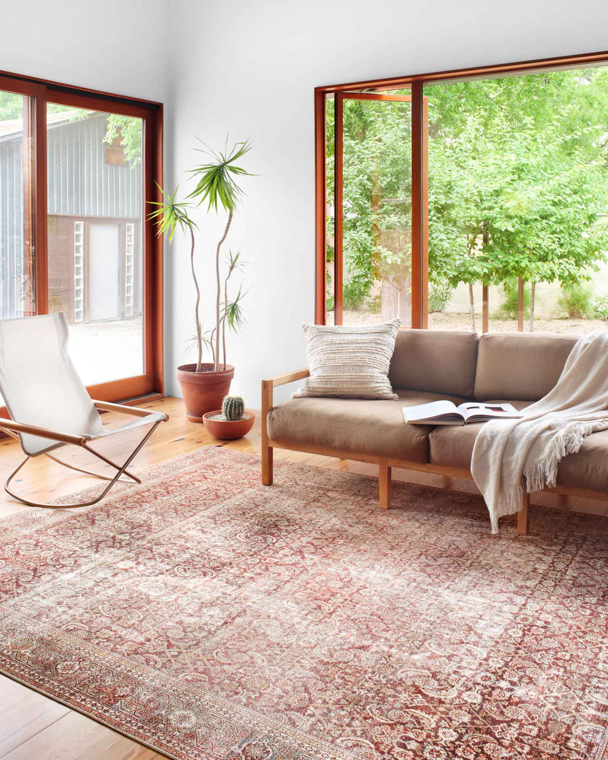 Rectangular traditional rug with red, cinnamon, and cream ornamental motifs in a living room