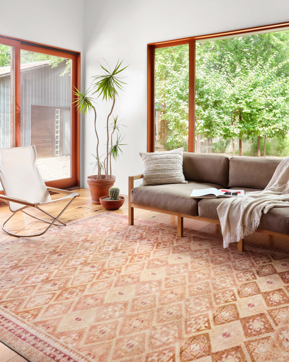 Natural beige and terracotta geometric area rug shown laid on a living room floor.